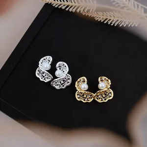 Primo piano di orecchini placcati oro e argento con perle e pietre di zircone.