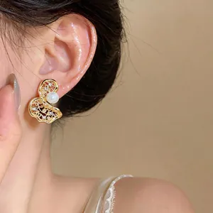 Primo piano di un orecchino traforato placcato oro 18k con perla e zircone.