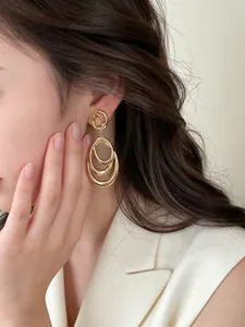 Detailed view of layered gold circular dangle earrings worn on a model's ear
