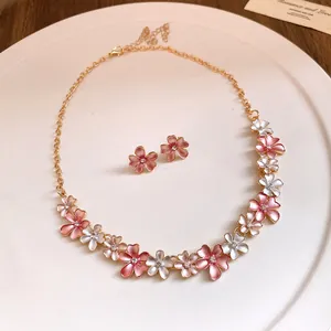 Macro view of a sweet pink and white enamel flower necklace and stud earrings set
