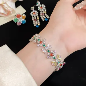 Detail shot of a colorful zircon flower bracelet and matching drop earrings on a wrist
