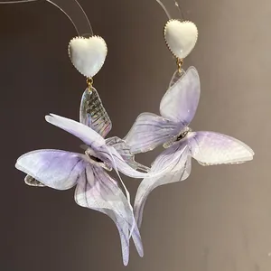Macro detail of ethereal purple fabric butterfly wings attached to white heart studs