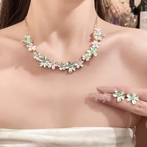 Detailed view of an elegant floral necklace and earring set shown on a model's neck area