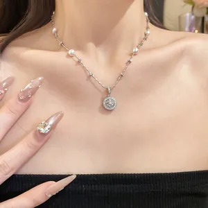 Detail view of an elegant pearl and zircon pendant necklace on model collarbone.