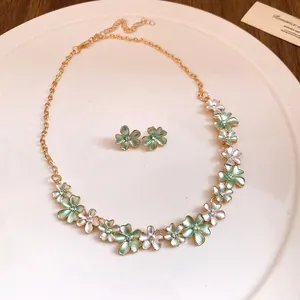Close-up of green and white enamel flower necklace and matching stud earring set