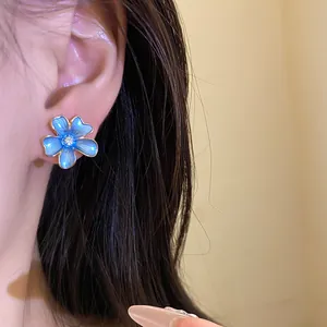 Detailed close-up view of a blue enamel flower earring with a sparkling zircon center