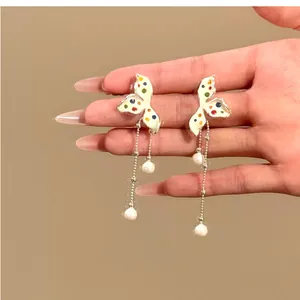 Detail view of butterfly wing earrings with colorful polka dots and pearl tassels.