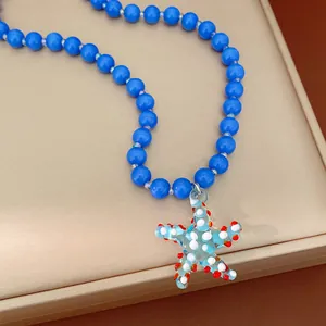 Detail shot of a blue beaded necklace with a light blue glass starfish pendant and dots.