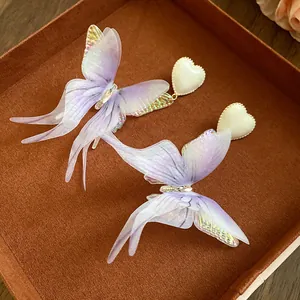 Detailed view of iridescent purple fabric butterfly wings on elegant heart earrings