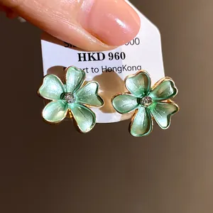 Detailed view of light green enamel flower stud earrings with a central clear zircon stone.