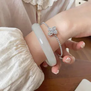 Primer plano de un brazalete de piedra ojo de gato blanco con pulsera plateada.