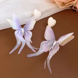 Detail view of ethereal purple fabric butterfly earrings with white heart studs and silver needle