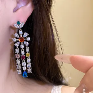 Close-up of elegant floral tassel earring with colorful zircons and blue teardrop