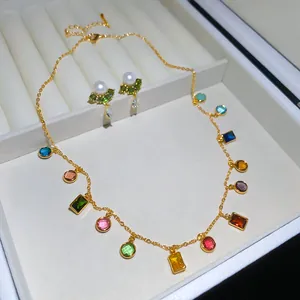 Close-up van goudvergulde ketting en oorbellen set met levendige gekleurde edelstenen