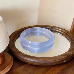 Primer plano de una pulsera de piedra de ojo de gato blanca translúcida en una bandeja espejo