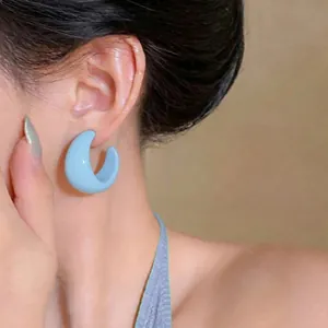 Sweet light blue C-shaped resin hoop earrings with glossy finish worn by model