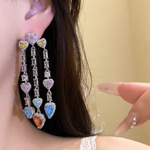Close-up of long tassel earrings featuring multi-colored heart-shaped zircon stones.