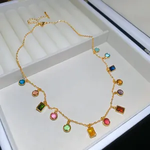 Detailweergave van een vergulde ketting met levendige veelkleurige kristallen bedels.