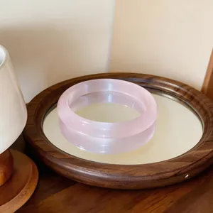 Elegante brazalete minimalista de piedra ojo de gato rosa en una bandeja de espejo de madera