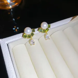 Detailopname van parel- en groene zirkonia-oorknopjes met waterdruppelhanger in 14k goud
