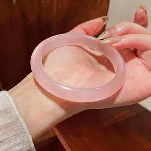 Vista detallada de una pulsera de piedra ojo de gato rosa translúcida en la muñeca