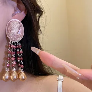 Vintage cameo profile earrings with elegant pink pearl tassels worn by an Asian model