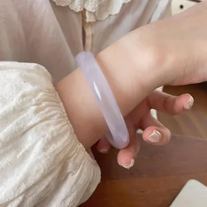 Primer plano de una pulsera de piedra ojo de gato blanca translúcida en la muñeca de una mujer
