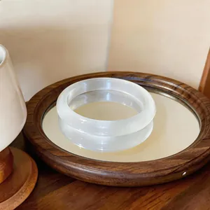 Primer plano de un brazalete de piedra ojo de gato blanco en una bandeja de madera con espejo