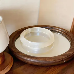 Detalle de brazalete de piedra de ojo de gato blanco translúcido en bandeja de madera