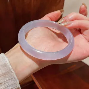 Vista detallada de un brazalete de piedra ojo de gato lavanda translúcida en la mano