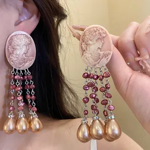 Vintage oval cameo drop earrings with elegant pearl tassels in a detail view.