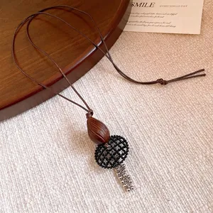 Vintage ethnic style long necklace with wooden bead and resin pendant on beige fabric.