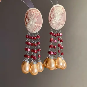 Detailed view of vintage cameo earrings with red beads and teardrop pearl tassels