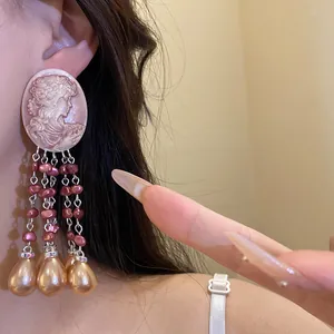 Detailed close-up shot of vintage oval cameo earrings with elegant pink and golden pearl tassels