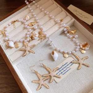 Elegantes Perlen-Schmuckset mit goldenen Seesternen und Muscheln in einer Holzschatulle
