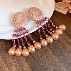 Macro detail of vintage-style oval cameo earrings featuring pink pearl tassel drops