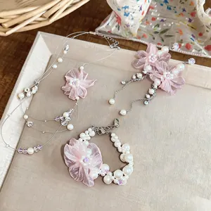 Detailansicht eines eleganten Schmucksets mit rosa Chiffonblumen und Perlen für Damen