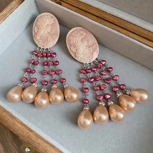 Close-up of vintage cameo relief and elegant pink/champagne pearl tassel details.