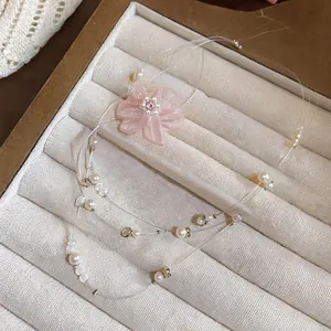 Detailansicht einer rosa Chiffonblumen-Halskette mit Perlenakzenten in einer Schmuckschale