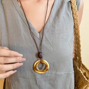 Close-up view of a retro ethnic style long necklace with a round resin pendant and wood bead.