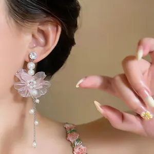 Elegante Nahaufnahme von rosa Chiffonblumen-Ohrringen mit weißen Perlen an einem Modell