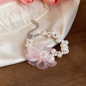 Elegantes Perlenarmband mit rosa Chiffonblume und Kristallen auf beigem Stoffdetailansicht