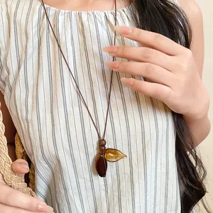 Detailed view of a vintage long necklace with resin leaf pendants and wooden beads