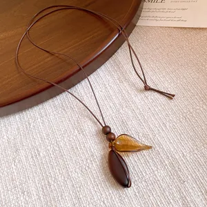 Macro view of vintage round wooden beads and amber resin leaf pendant on a cord