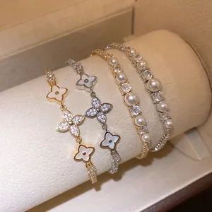 Detailed view of four elegant 18k gold plated bracelets with flower and pearl accents