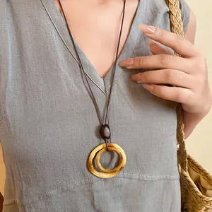 Close-up of retro ethnic style resin necklace with bamboo ring pendant on linen dress