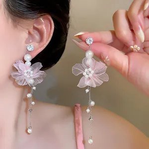 Nahaufnahme von rosa Chiffonblumen-Ohrringen mit eleganten Perlenquasten und Kristallsteckern