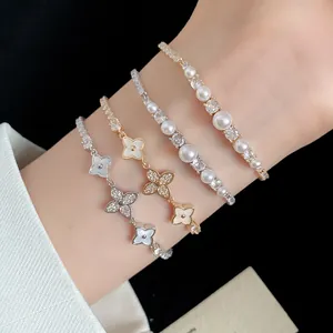 Detailed view of 18k gold plated zircon flower and pearl bracelets on wrist.