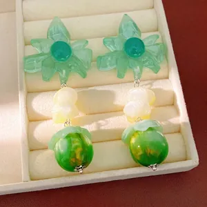 Orecchini a fiore in resina verde con perle gialle e sfere verdi su vassoio bianco