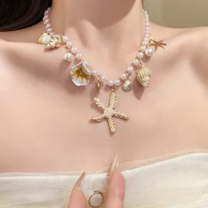 Detailansicht einer eleganten Perlenkette mit Seestern- und Muschelanhängern am Hals.